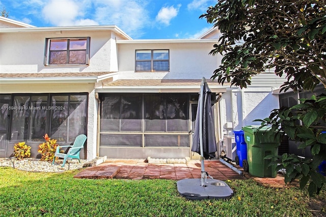 rear view of property featuring a yard and a sunroom