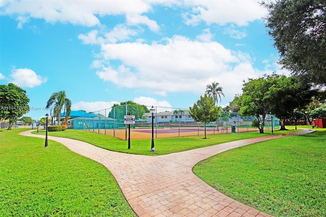 view of property's community with a yard and tennis court