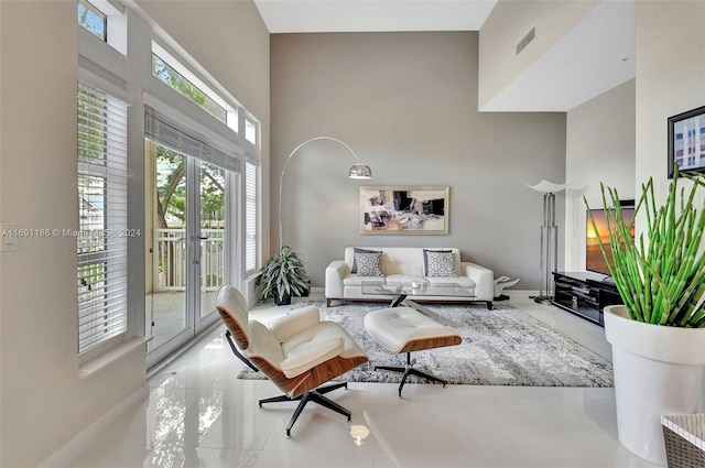 sitting room with a wealth of natural light, french doors, and a towering ceiling