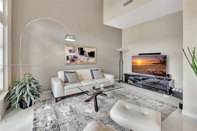 living room featuring plenty of natural light, light tile patterned flooring, and a towering ceiling