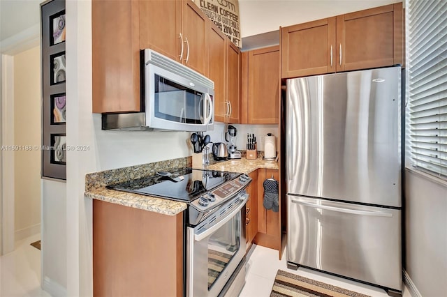 450 N Federal Hwy Unit 104N, Boynton Beach, FL 33435 - kitchen with appliances with stainless steel finishes, light stone countertops, brown cabinetry, and light tile patterned flooring