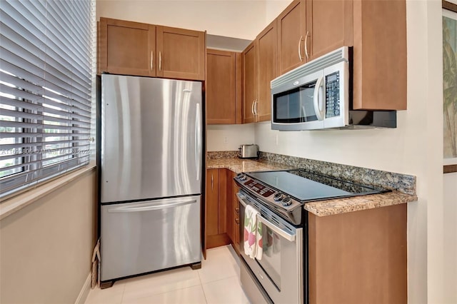 kitchen with dark stone countertops, light tile patterned flooring, and appliances with stainless steel finishes