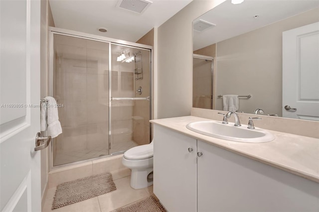 bathroom featuring toilet, vanity, tile patterned floors, and a shower with shower door