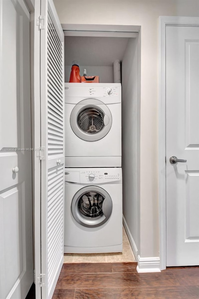 laundry area featuring dark hardwood / wood-style flooring and stacked washer and clothes dryer