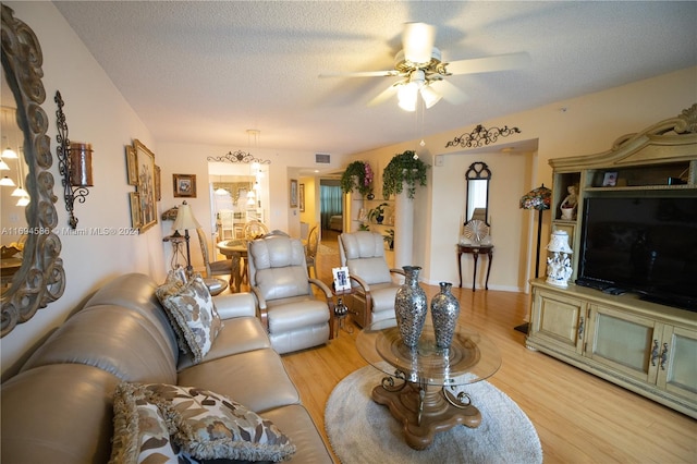 living room featuring a textured ceiling, light hardwood / wood-style flooring, and ceiling fan