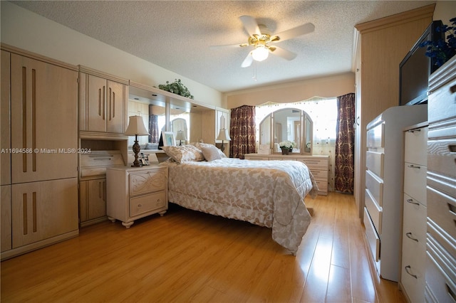 bedroom featuring ceiling fan, light wood-type flooring, a textured ceiling, and multiple windows