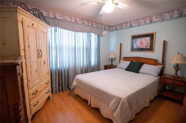 bedroom with a textured ceiling, light hardwood / wood-style floors, and ceiling fan