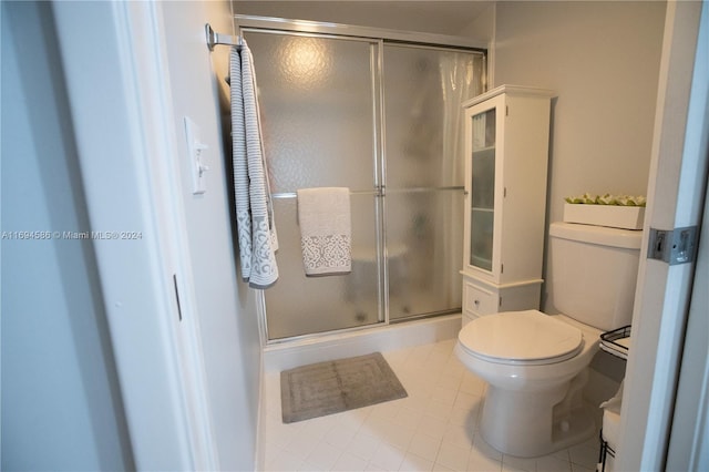 bathroom with tile patterned floors, a shower with shower door, and toilet