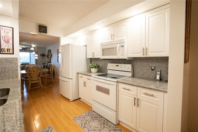 kitchen with pendant lighting, white appliances, light wood-type flooring, light stone counters, and white cabinetry