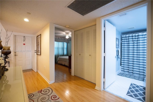 corridor featuring light wood-type flooring and a textured ceiling