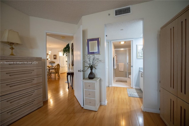 corridor with light hardwood / wood-style flooring and a textured ceiling