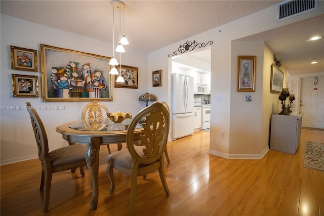 dining room with a textured ceiling and light wood-type flooring