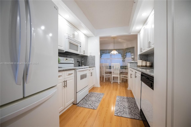 kitchen featuring light stone counters, white appliances, light hardwood / wood-style flooring, white cabinets, and hanging light fixtures