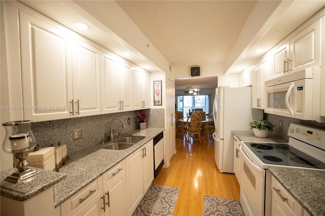 kitchen featuring white appliances, backsplash, white cabinets, sink, and light hardwood / wood-style flooring