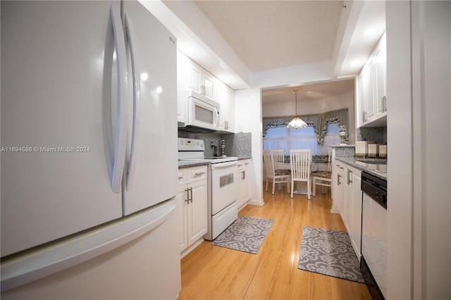 kitchen with pendant lighting, white appliances, light hardwood / wood-style floors, light stone counters, and white cabinetry