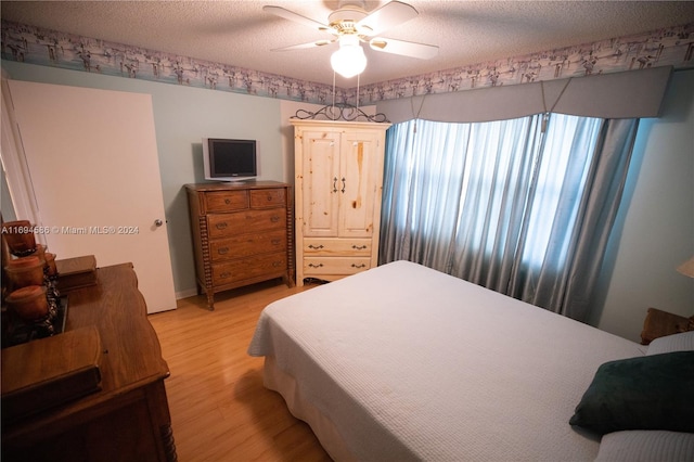 bedroom featuring ceiling fan, light hardwood / wood-style flooring, and a textured ceiling