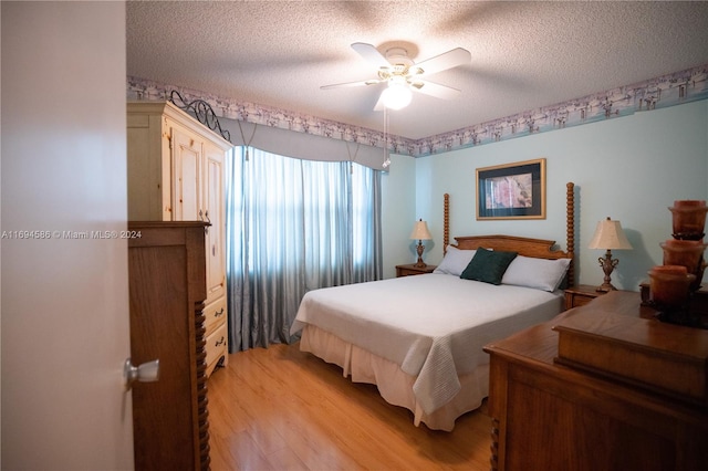 bedroom with ceiling fan, light hardwood / wood-style floors, and a textured ceiling