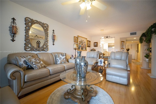 living room featuring ceiling fan, light hardwood / wood-style floors, and a textured ceiling