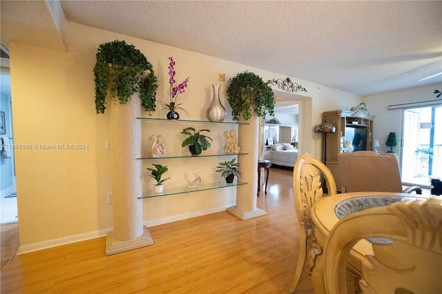 interior space with hardwood / wood-style floors, a textured ceiling, decorative columns, and ceiling fan