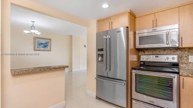 kitchen with appliances with stainless steel finishes, backsplash, light brown cabinets, light tile patterned floors, and pendant lighting