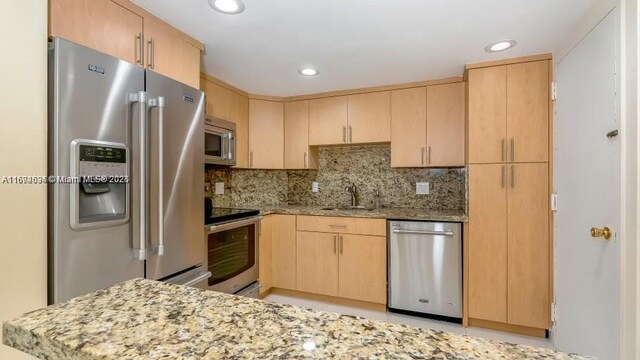 kitchen with sink, light brown cabinetry, light stone countertops, and appliances with stainless steel finishes