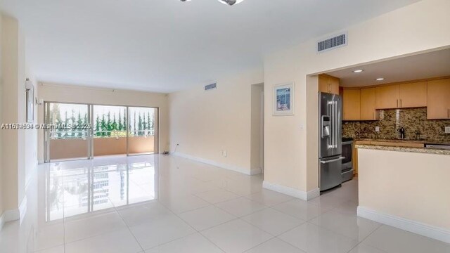 kitchen featuring decorative backsplash, light tile patterned floors, stainless steel appliances, and light brown cabinetry