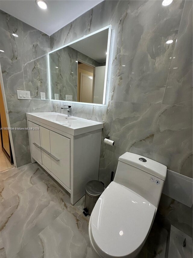 bathroom with toilet, vanity, tile walls, and walk in shower