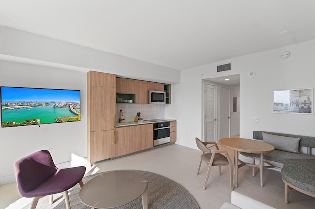 interior space featuring decorative backsplash, sink, light tile patterned flooring, and stainless steel appliances