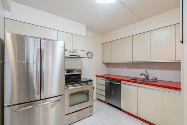 kitchen featuring sink, stainless steel appliances, range hood, a textured ceiling, and light tile patterned floors