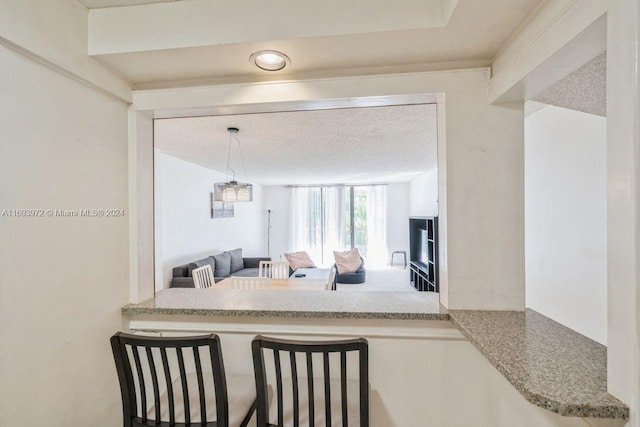 kitchen with decorative light fixtures, light stone counters, and a textured ceiling