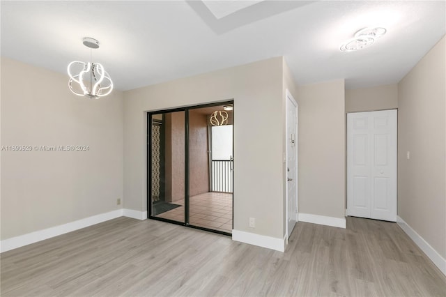 empty room featuring light wood-type flooring and an inviting chandelier