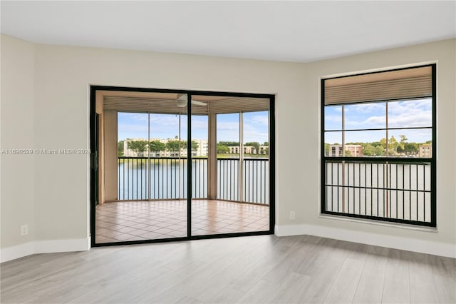 unfurnished room featuring light hardwood / wood-style floors, a water view, and a wealth of natural light