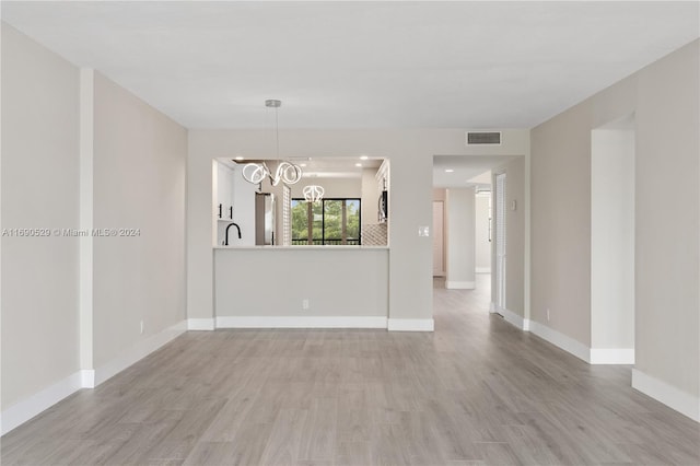 spare room with a chandelier and light hardwood / wood-style flooring