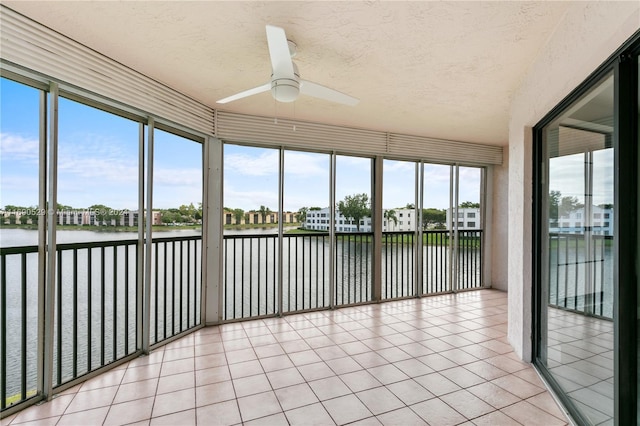 unfurnished sunroom with ceiling fan and a water view