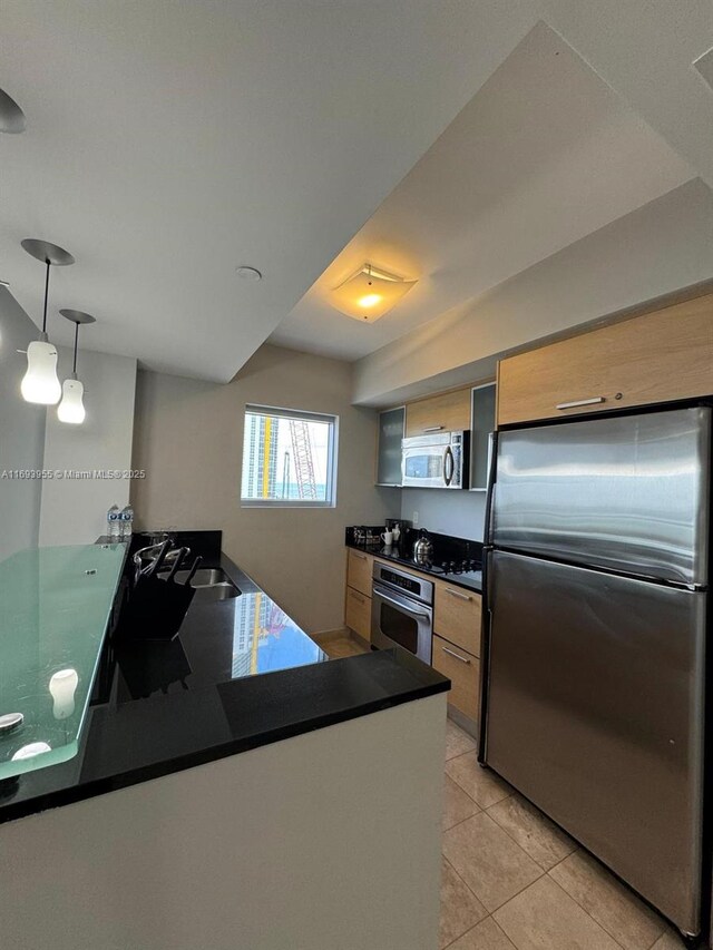 kitchen with pendant lighting, sink, stainless steel appliances, light tile patterned flooring, and kitchen peninsula