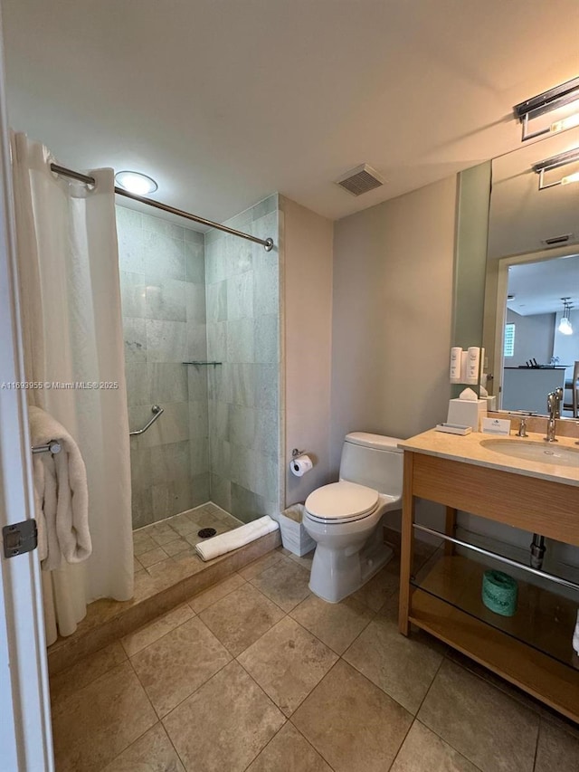 bathroom with vanity, toilet, tile patterned flooring, and a tile shower