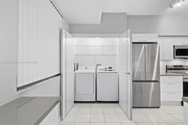 interior space featuring independent washer and dryer, stainless steel appliances, white cabinetry, and light tile patterned flooring