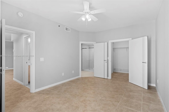 unfurnished bedroom featuring ceiling fan, light tile patterned floors, a spacious closet, and connected bathroom