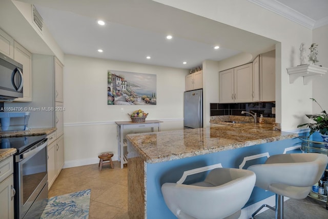 kitchen featuring kitchen peninsula, a breakfast bar, light tile patterned flooring, and stainless steel appliances