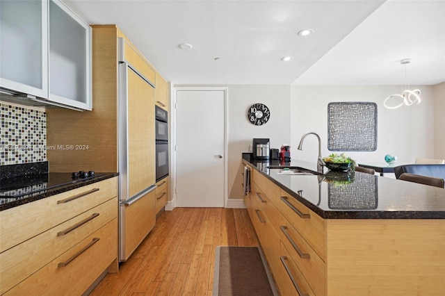 kitchen with sink, light hardwood / wood-style flooring, backsplash, black double oven, and pendant lighting