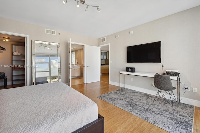 bedroom with connected bathroom and hardwood / wood-style floors