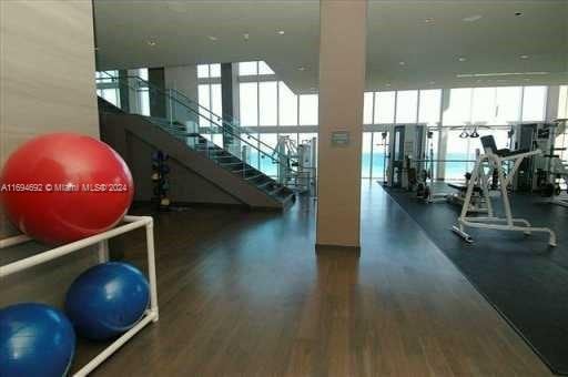 workout area with a wealth of natural light, dark hardwood / wood-style flooring, and expansive windows