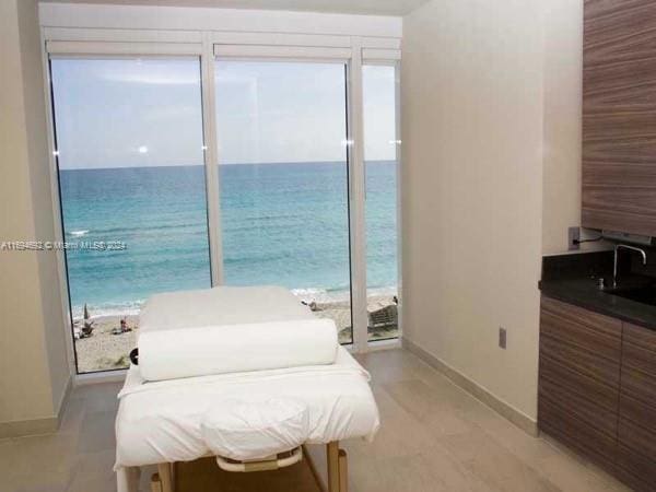 bedroom featuring a water view, a beach view, and sink