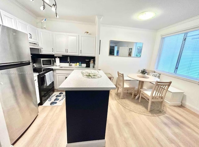 kitchen featuring white cabinetry, a center island, light hardwood / wood-style floors, appliances with stainless steel finishes, and ornamental molding