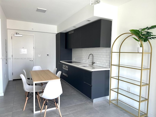 kitchen featuring decorative backsplash, dark tile patterned flooring, oven, and sink