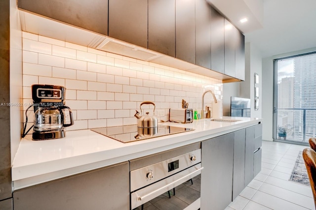 227 NE 2nd St Unit 1705, Miami, FL 33132 - kitchen featuring oven, black electric stovetop, tasteful backsplash, a sink, and light countertops