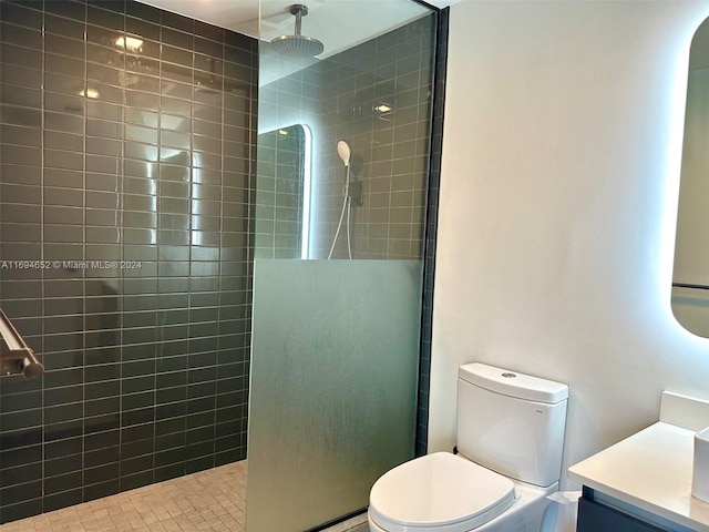 bathroom with a tile shower, vanity, and toilet