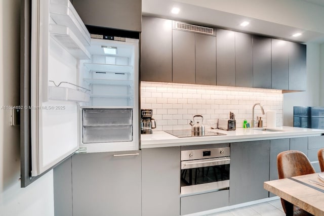 227 NE 2nd St Unit 1705, Miami, FL 33132 - kitchen with a sink, stainless steel oven, black electric stovetop, decorative backsplash, and recessed lighting