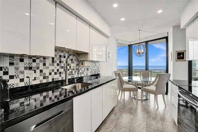 kitchen with a water view, white cabinetry, dark stone countertops, and pendant lighting