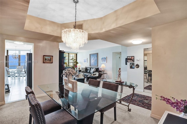 carpeted dining space with an inviting chandelier and a tray ceiling